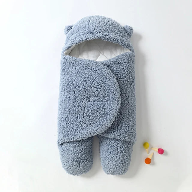 Blue baby wrap blanket showing its bear-ear hood, white lining, and overlapping front closure.