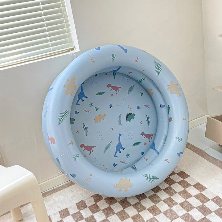 Blue round inflatable pool with colorful dinosaur and leaf prints on the sides and base.