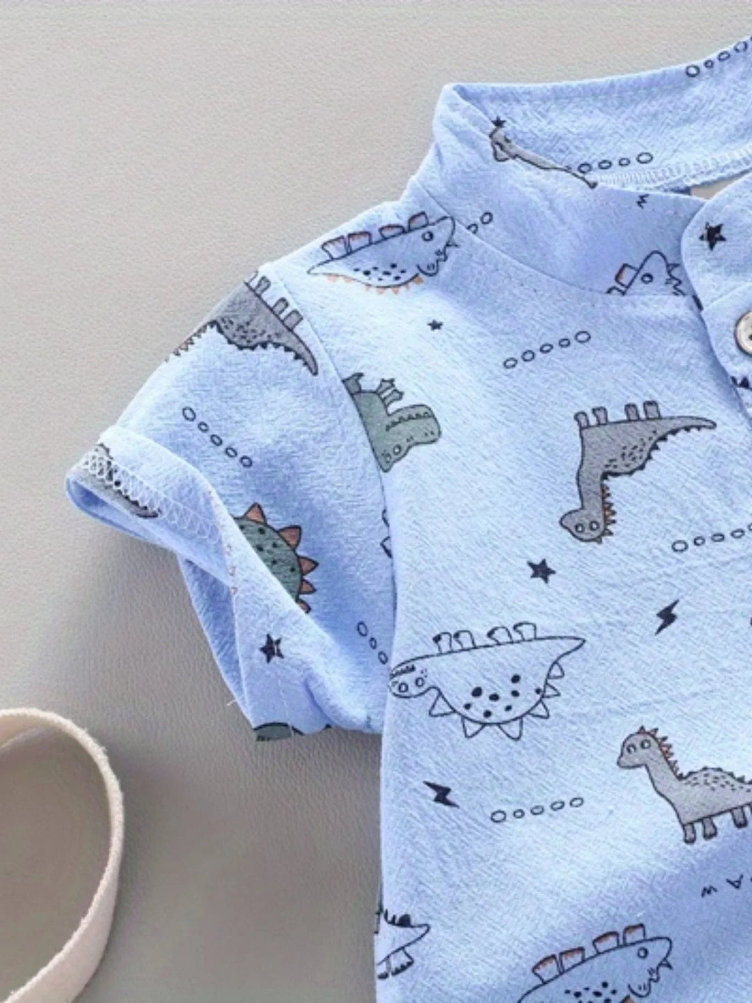 Cuffed short sleeve and dinosaur print on the blue shirt