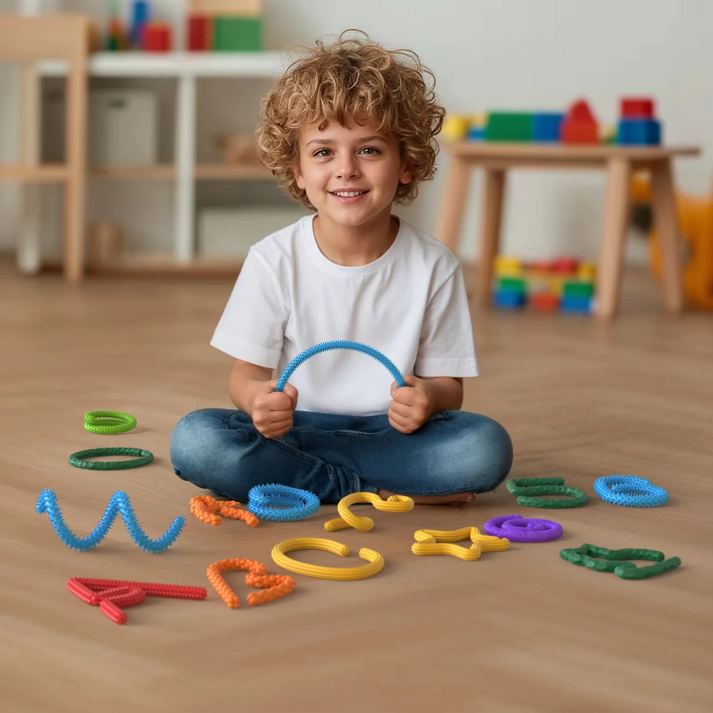 Child seated on the floor holding a curved blue fidget stick, surrounded by colorful stick shapes.