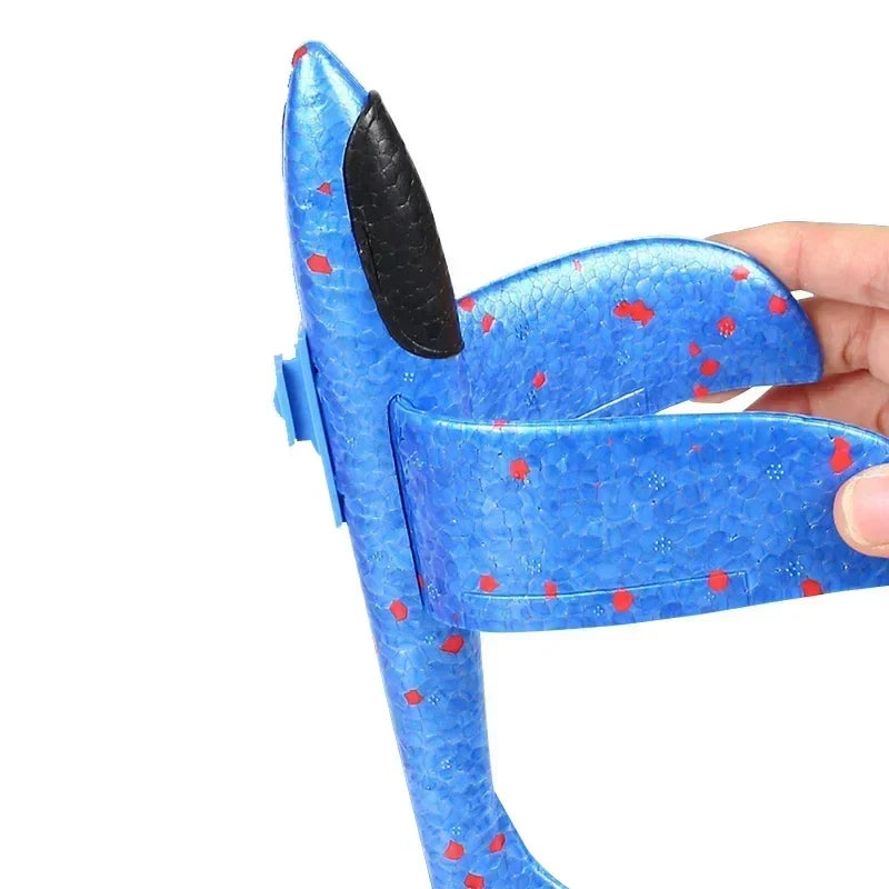 A hand flexing the wing of a blue foam airplane with red speckles
