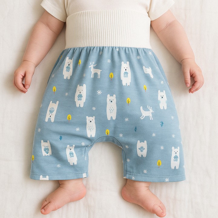 Baby wearing blue forest-animal training pants with a wide white waistband