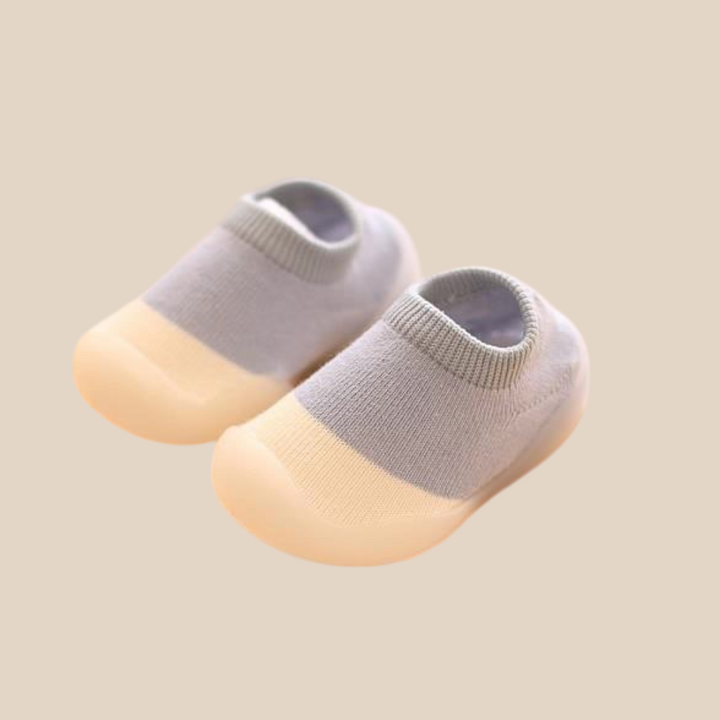 Blue-gray slip-on baby shoes showing low-cut knit uppers and cream-colored soles.