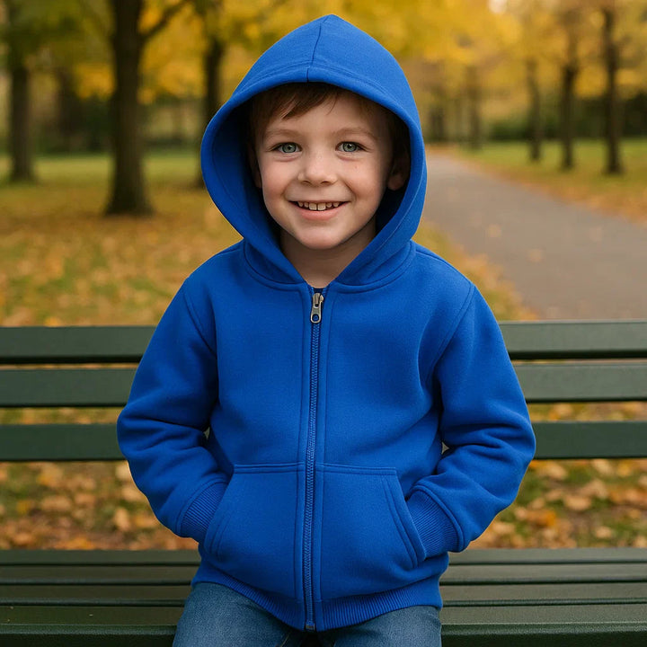 Child seated on a park bench wearing a blue zip-up hoodie with the hood raised.
