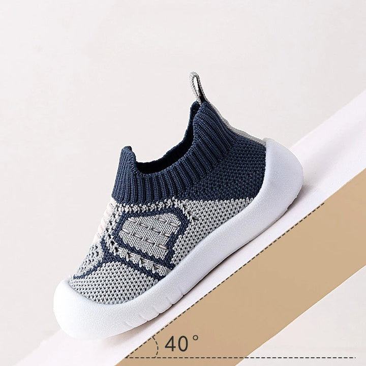 Blue knit slip-on shoe with a white sole shown on an angled platform