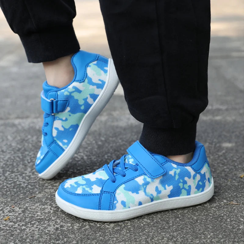Blue camouflage sneakers worn with black pants, showing the sides and strap closures
