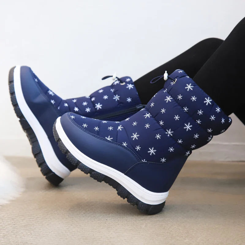 Blue snowflake-print snow boots worn with black leggings, showing thick treaded soles