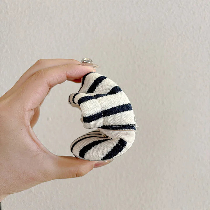 Blue-and-cream striped baby shoe bent in half to show its flexibility