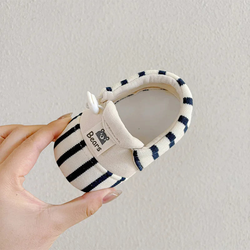 Top view of a blue-and-cream striped baby shoe with a small side bow