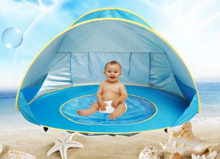 Baby sitting in the circular bath inside a blue beach tent