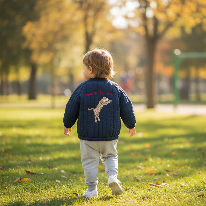 Child wearing the blue quilted jacket with tiger embroidery outdoors