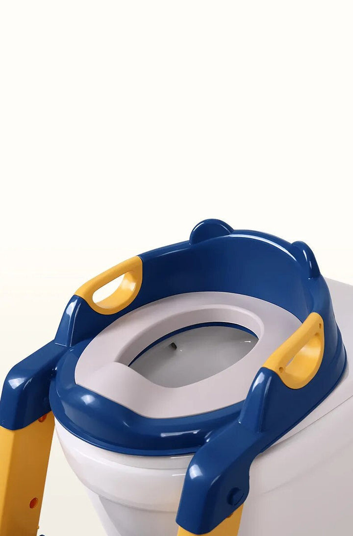 Blue toilet training seat with a gray insert and yellow side handles fitted over a toilet