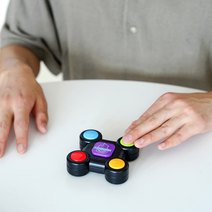 Player pressing the green button on a memory game placed on a white table