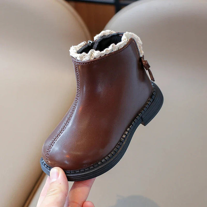 Side view of a brown ankle boot with a black sole and cream ankle trim