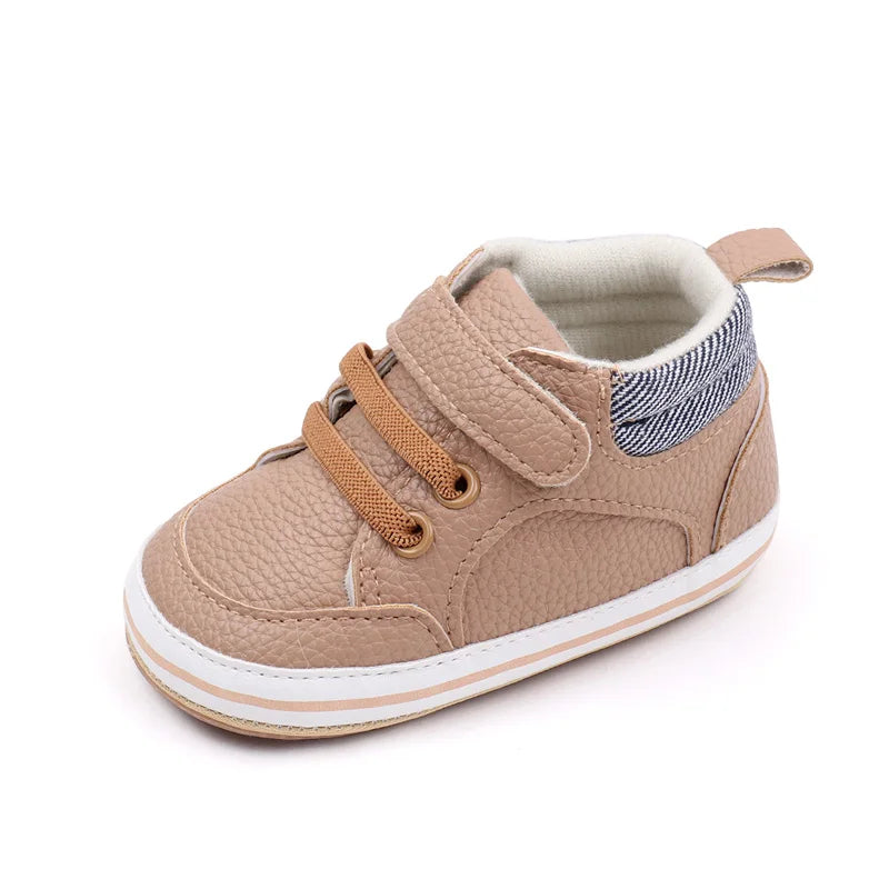 Brown baby sneaker showing the hook-and-loop strap, lace detailing, and white sole trim