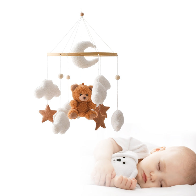 Brown bear mobile with clouds, stars and a crescent moon shown above a sleeping baby