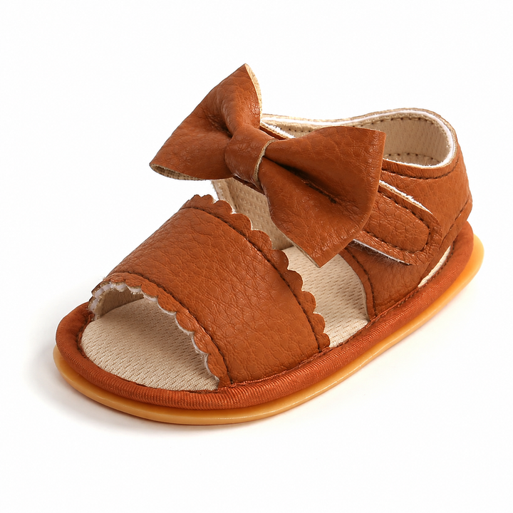 Brown baby sandal with a bow, scalloped front strap, and open toe