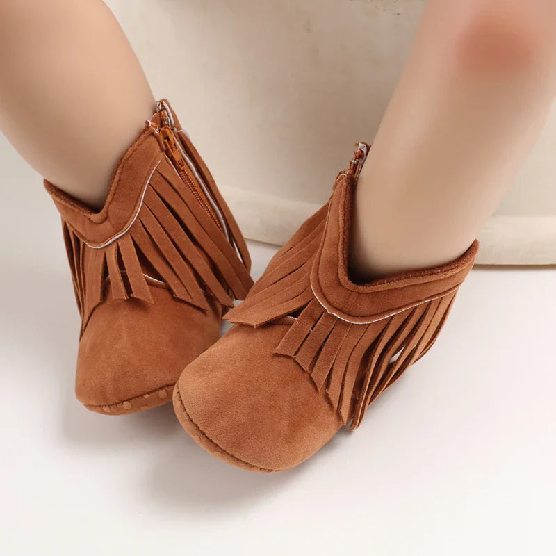 Brown fringe cowboy boots worn on a baby&