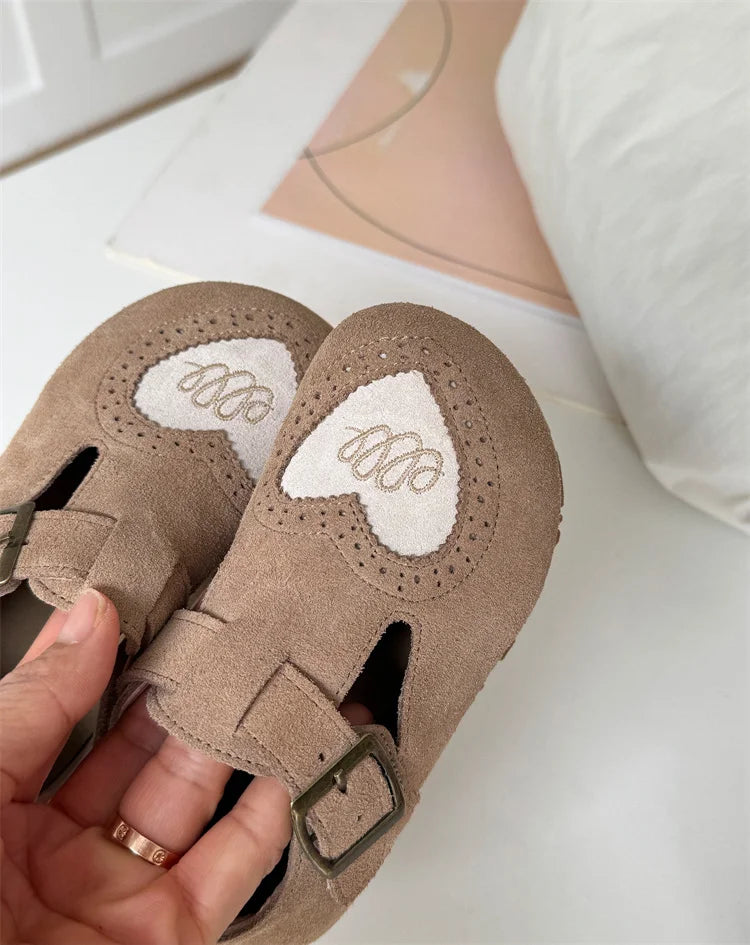 Brown shoe pair held close to show rounded toes and white heart details