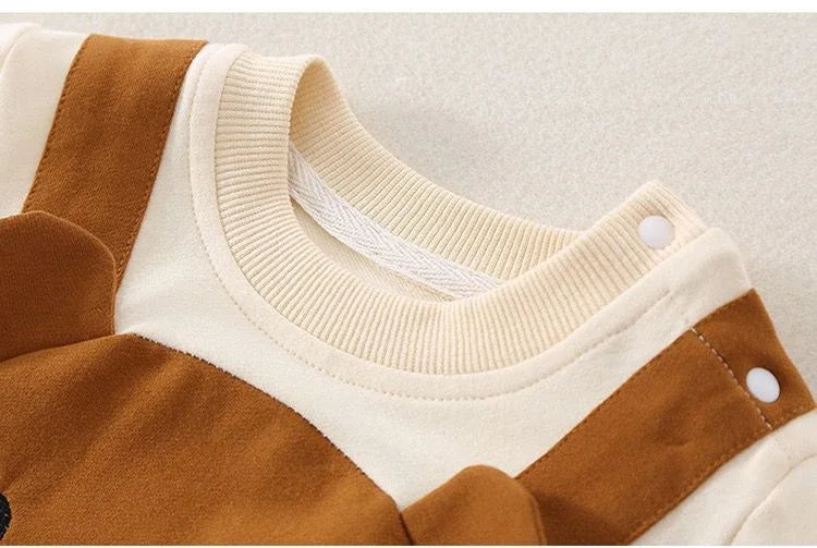 Close-up of the cream ribbed neckline and shoulder snaps on the brown baby jumpsuit