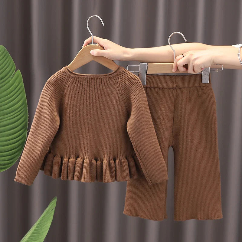 Back view of a brown knit sweater and matching pants on hangers