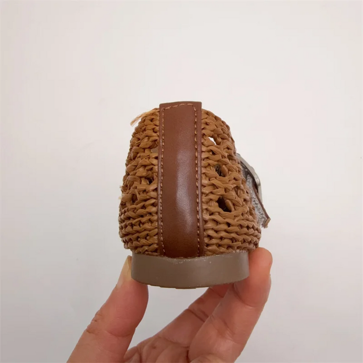 Rear view of a brown Mary Jane flat showing its woven heel and vertical trim