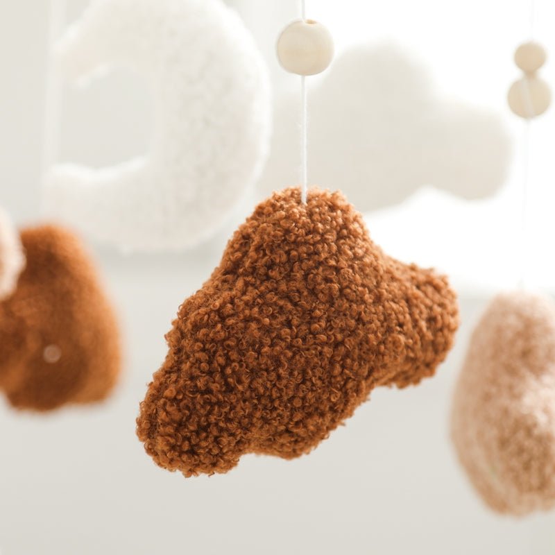 Close-up of brown textured fabric and hanging beads on the baby mobile