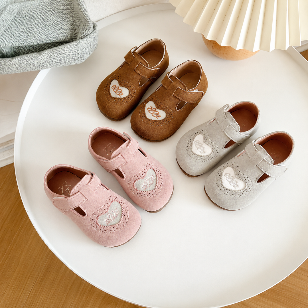 Brown, pink, and gray heart-detail shoe pairs arranged on a round white table