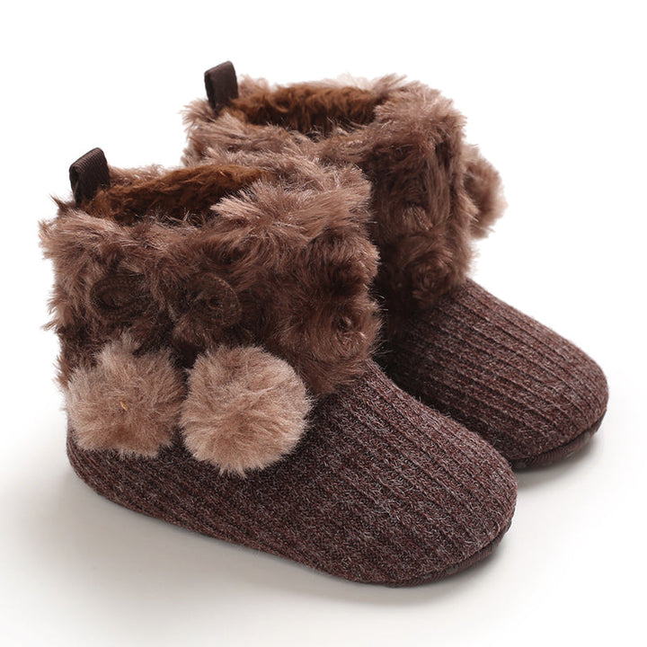 Brown baby boots with plush ankle cuffs and matching pom-poms
