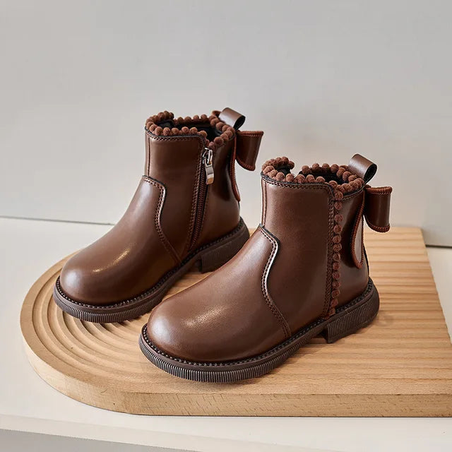 Pair of brown ankle boots with a visible side zipper, back bows, and dark soles