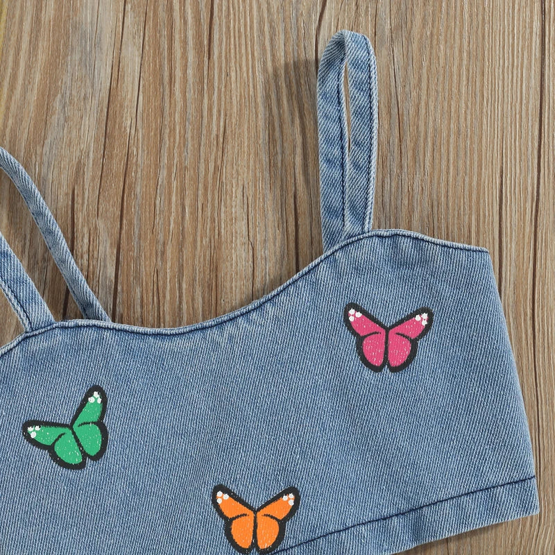 Close-up of thin shoulder straps and butterfly embroidery on the blue denim top