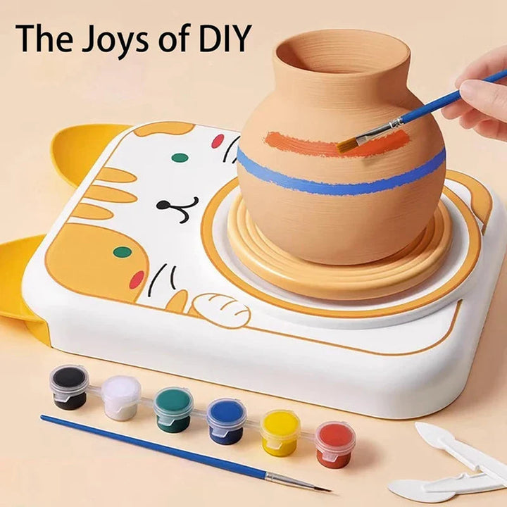 Brush painting colored stripes on a clay vase on the cat-themed pottery wheel