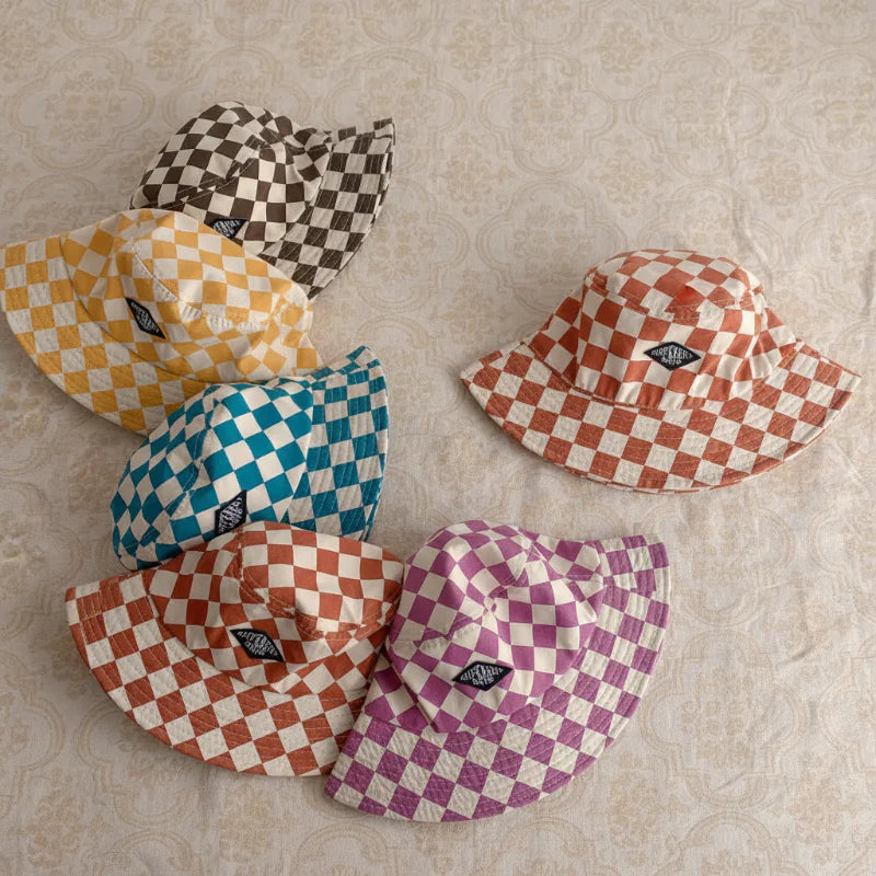Six checkered bucket hats arranged on a patterned surface
