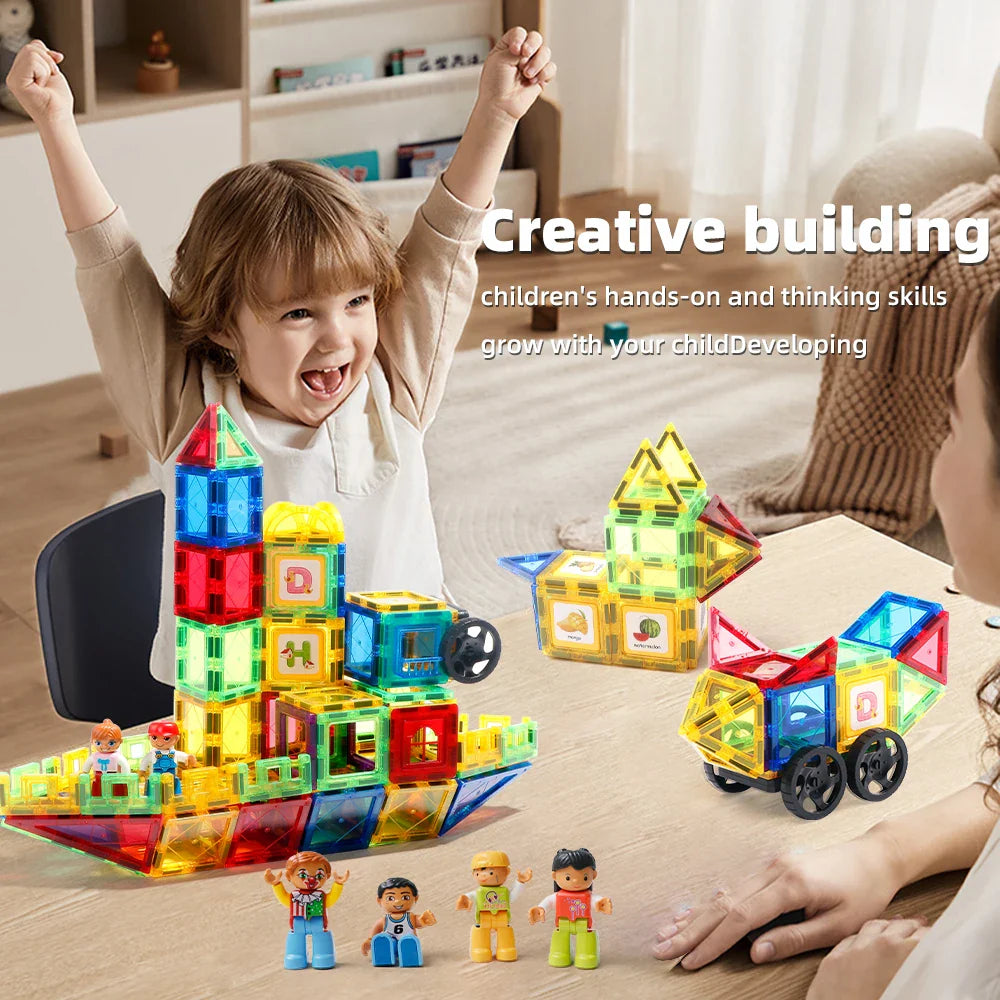 Child and adult beside magnetic tile towers, houses, wheeled builds, and small figures