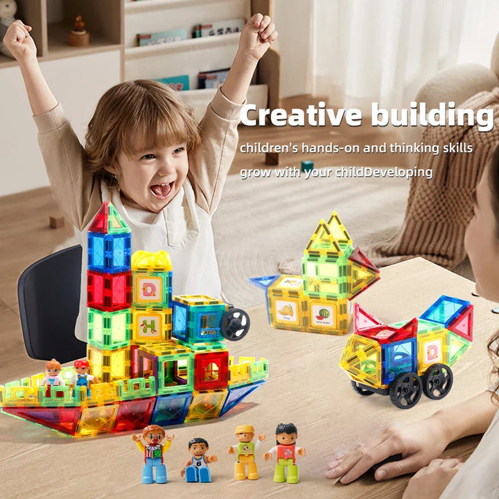 Child and adult beside magnetic tile towers, houses, wheeled builds, and small figures