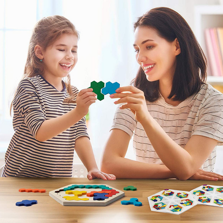 Child and adult holding colorful wooden puzzle pieces beside a hexagonal board.