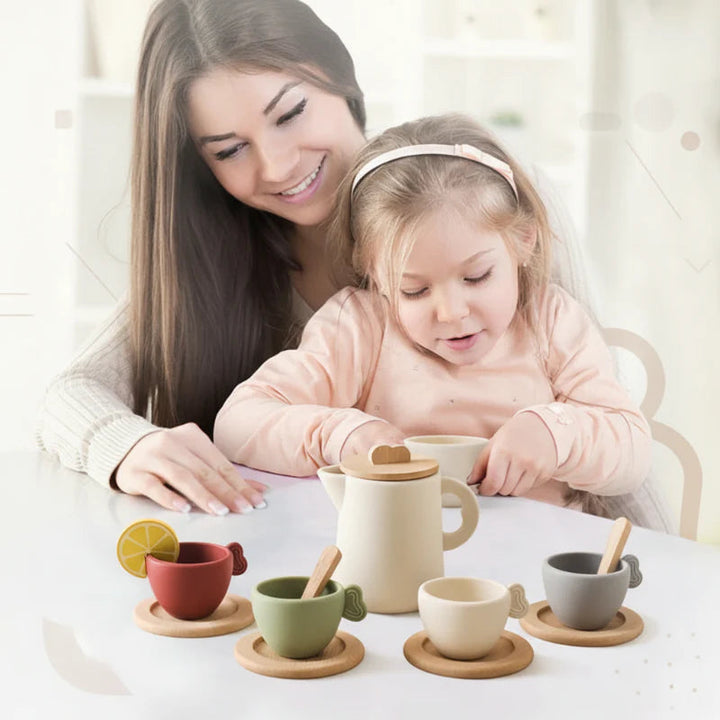 Adult and child playing with colorful tea cups and a cream-colored pitcher at a table