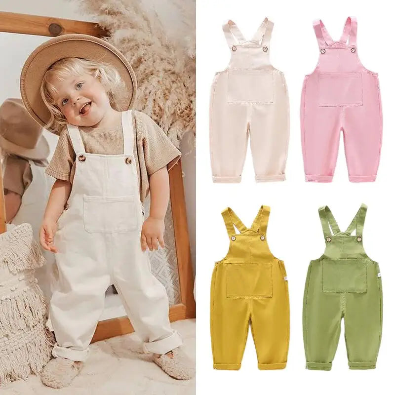 Child wearing cream overalls beside cream, pink, yellow, and green overalls