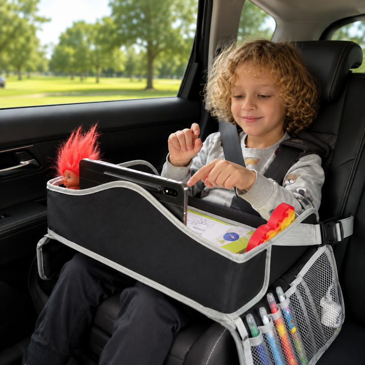 Child using a black travel tray with a tablet and toys while seated in a car