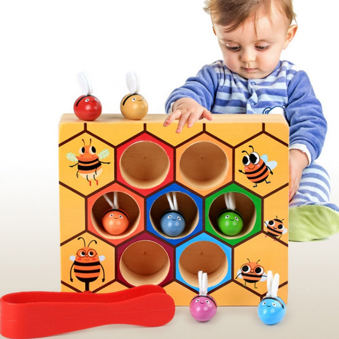 Child exploring a wooden bee sorting board with colorful bees and red tweezers