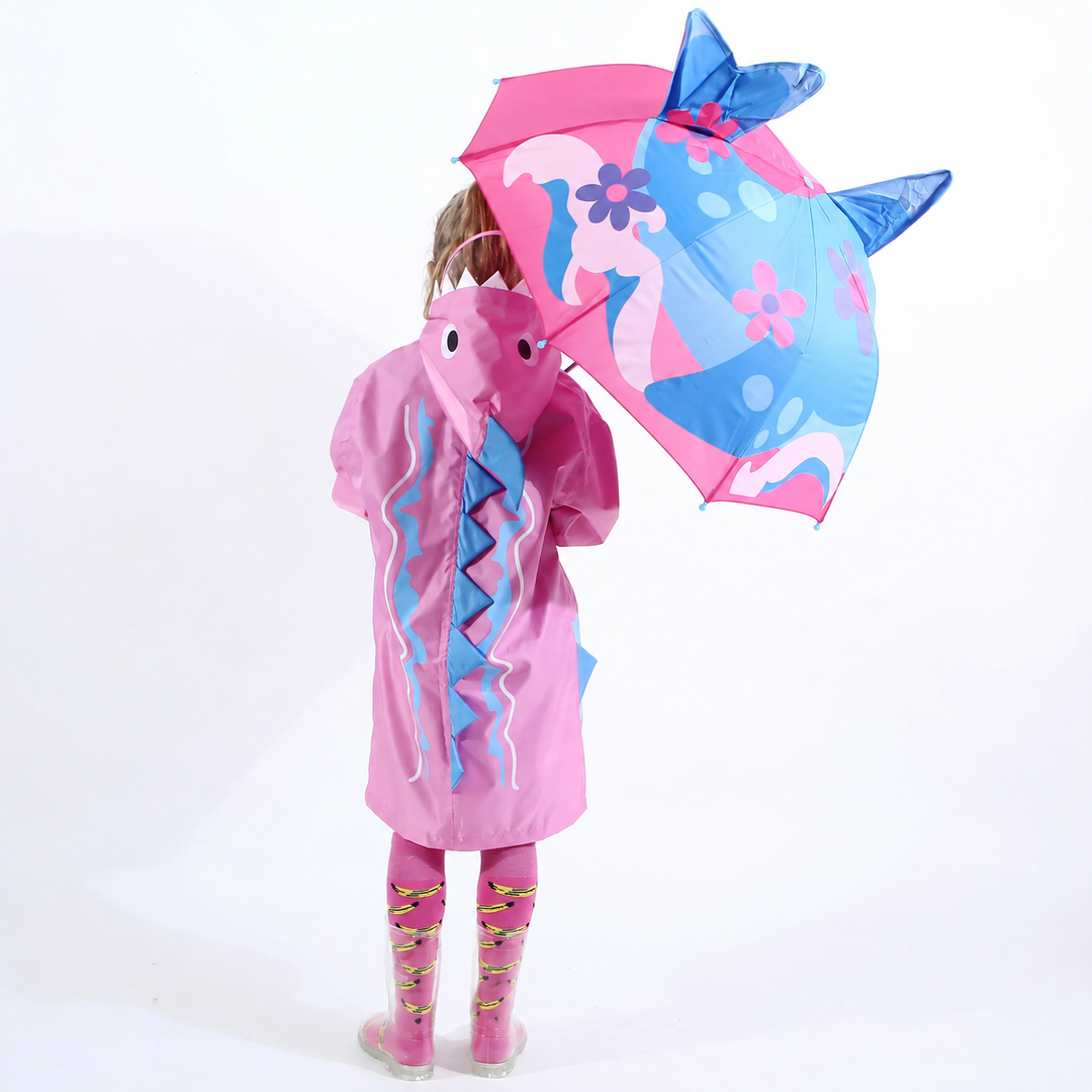 Child in a pink raincoat holding a blue and pink floral shark umbrella