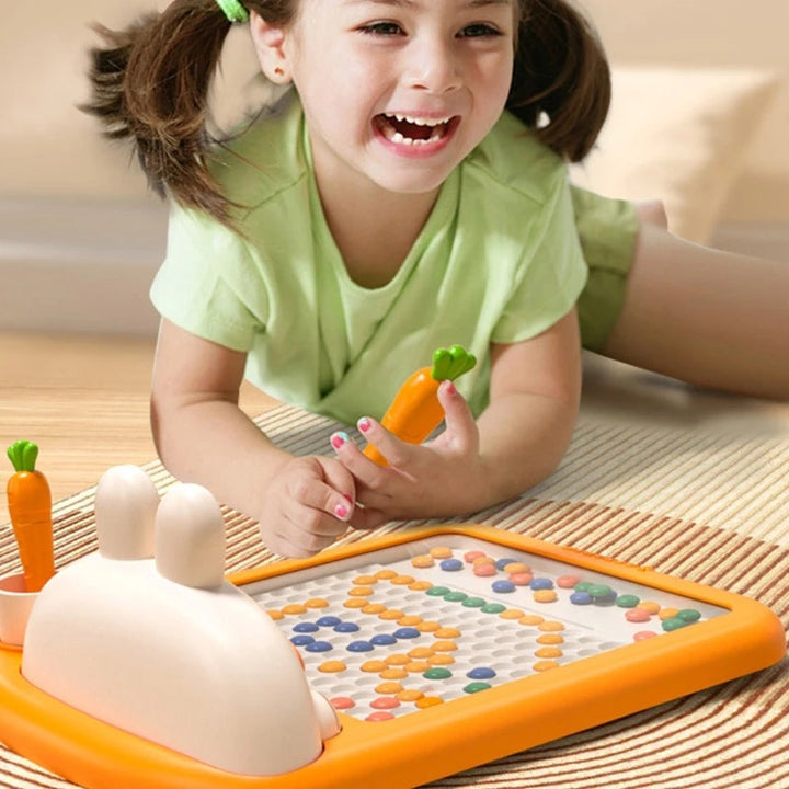 Child holding a carrot-shaped pen above a colorful bunny magnetic drawing board