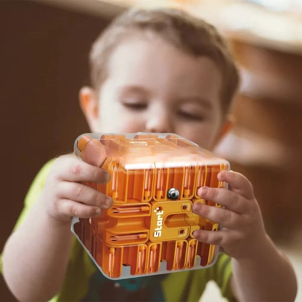 Child holding an orange puzzle cube with a ball visible in the maze