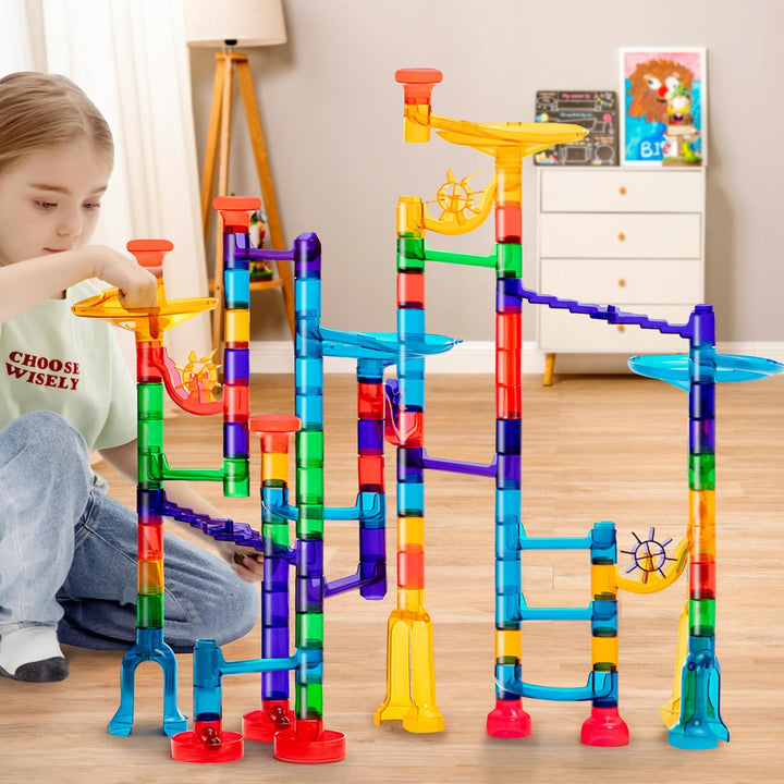 Child playing with a tall multicolor marble run on the floor