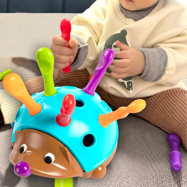 Child holding a red quill beside a hedgehog toy with open slots