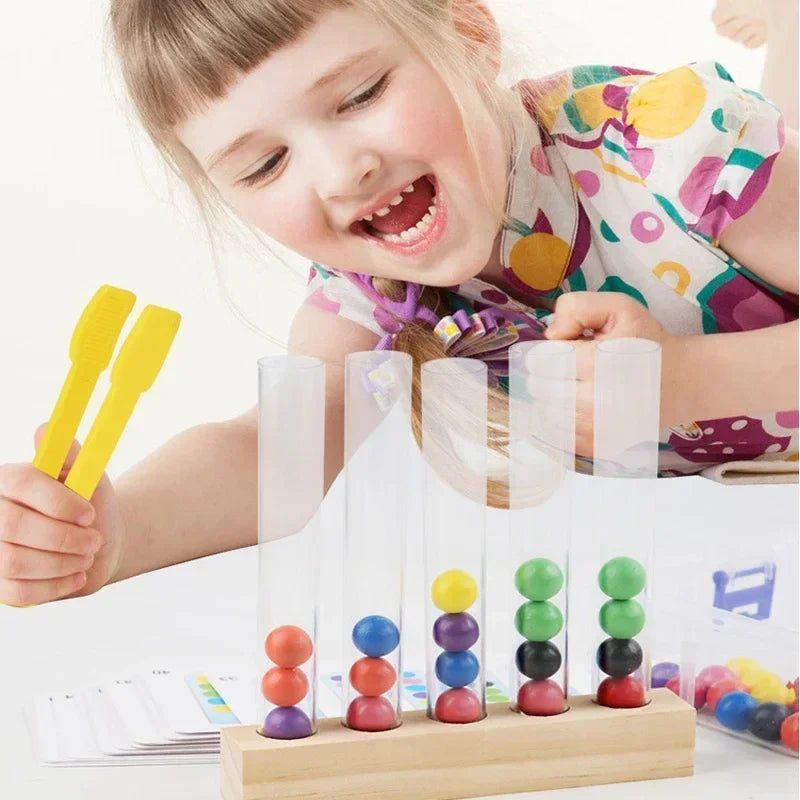 Child using a yellow clip beside clear tubes filled with colored wooden balls