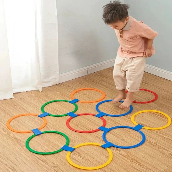 Child stepping through colorful hoops joined with blue clips on a wooden floor