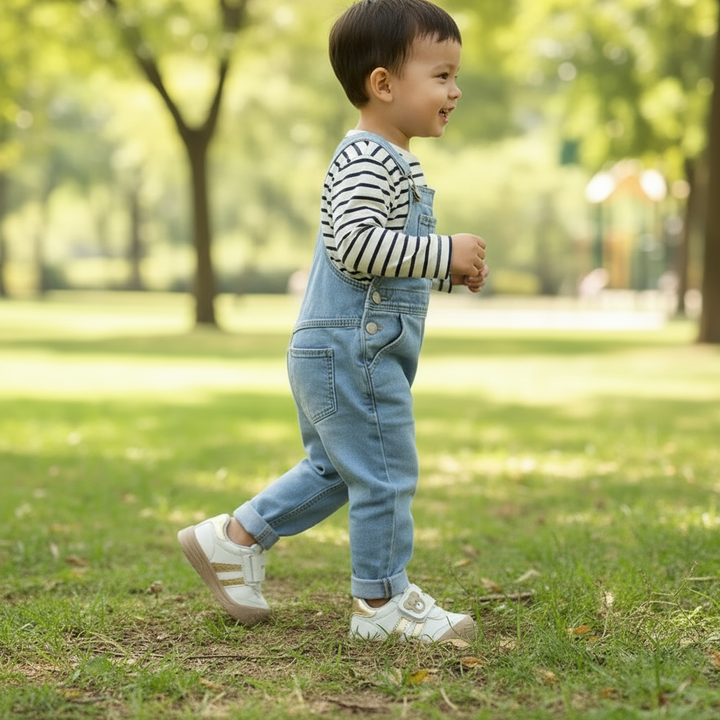 Child wearing cream bear-detail sneakers while walking on grass