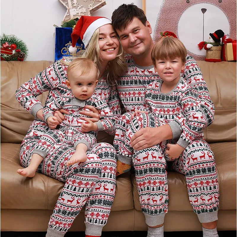 Two adults, a baby, and a child in matching Christmas pajamas on a couch