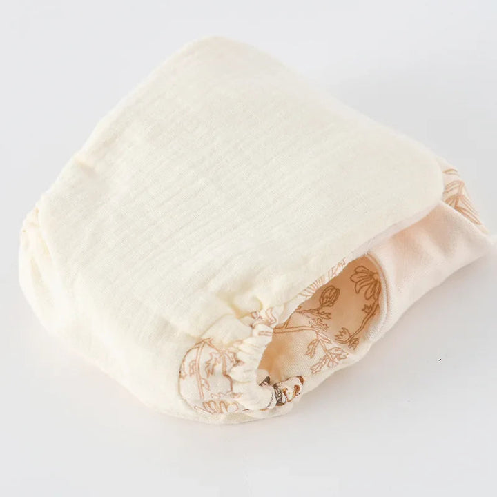 Folded cloth diaper showing its cream cotton lining and gathered leg opening